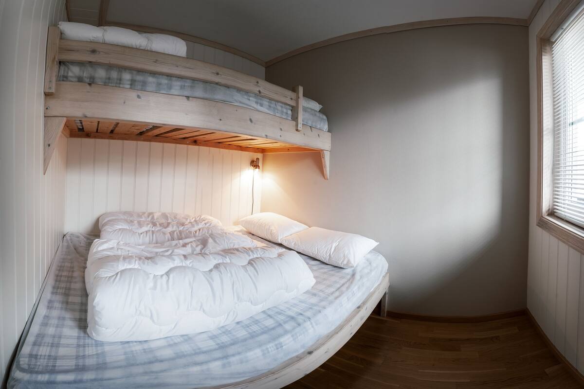 A bunk bed with a headboard and a bedside table with a lamp.
