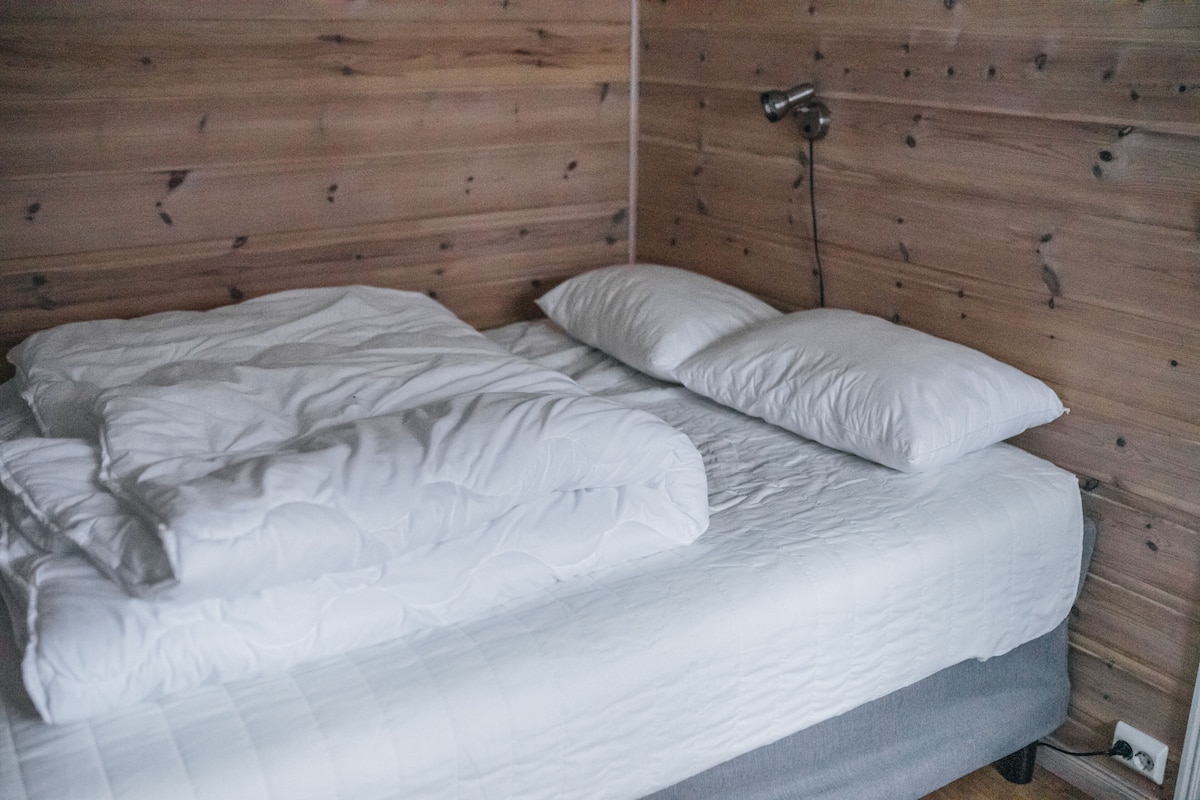 A bed with white bedding in a room with wooden panel walls.