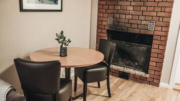Comedor con una mesa redonda de madera, dos sillas negras y una pequeña planta en maceta.
