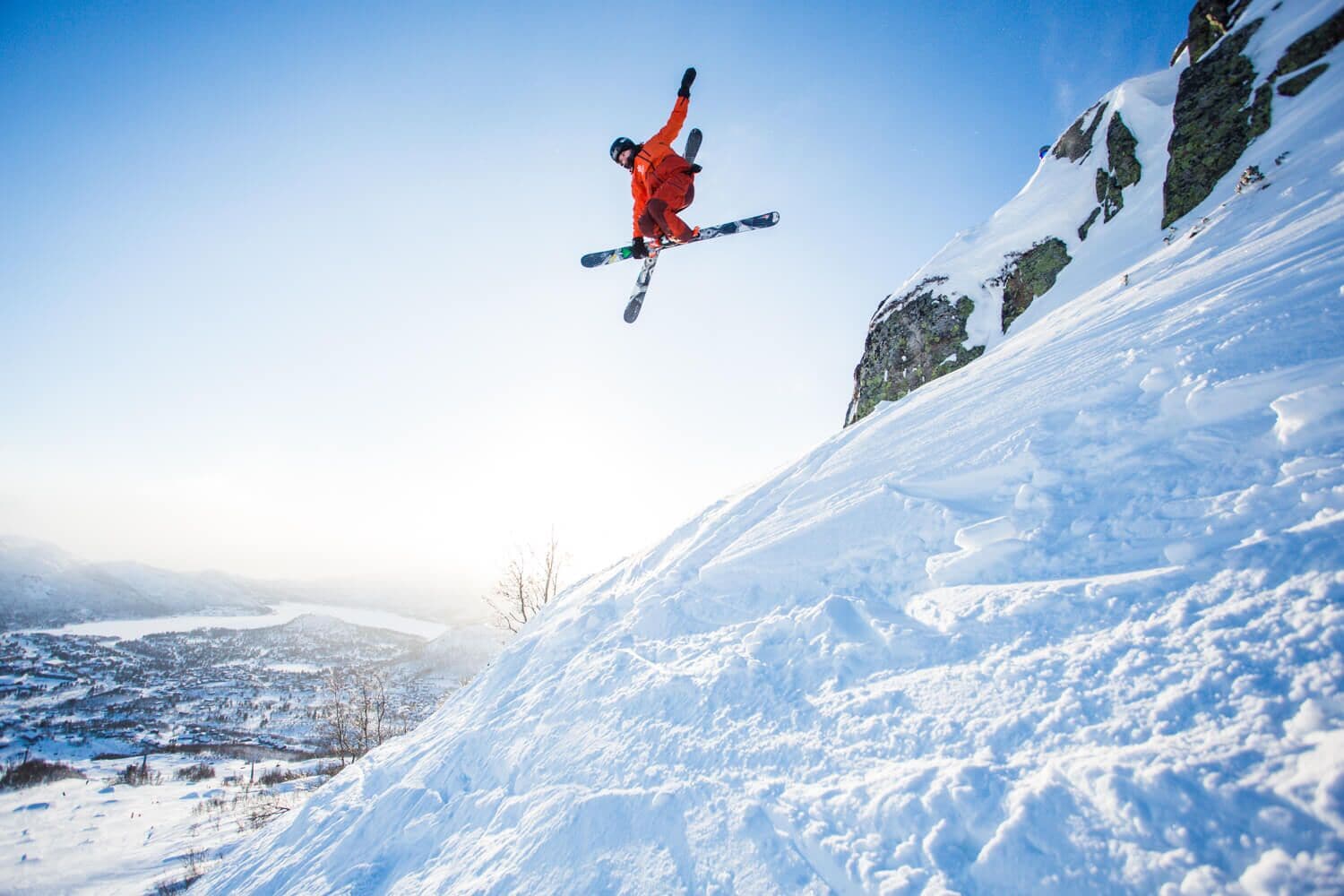 A person skiing on a snowy slope with a clear sky.