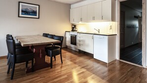Una cocina moderna con armarios blancos, una mesa de comedor de madera y sillas negras.