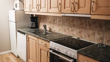A kitchen with wooden cabinets, a microwave, a coffee maker, a sink, and a dishwasher.