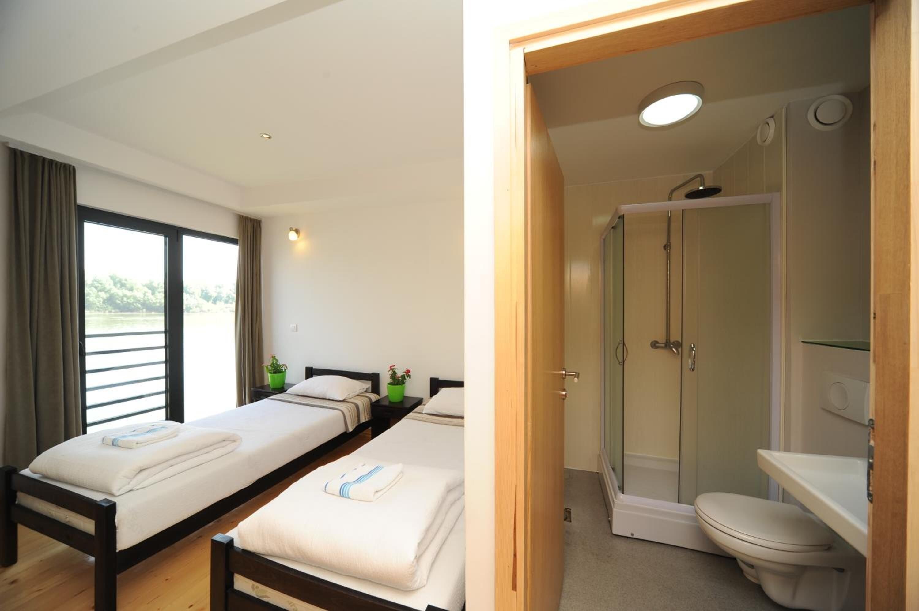 A hotel room with two beds, a shower, and a toilet.