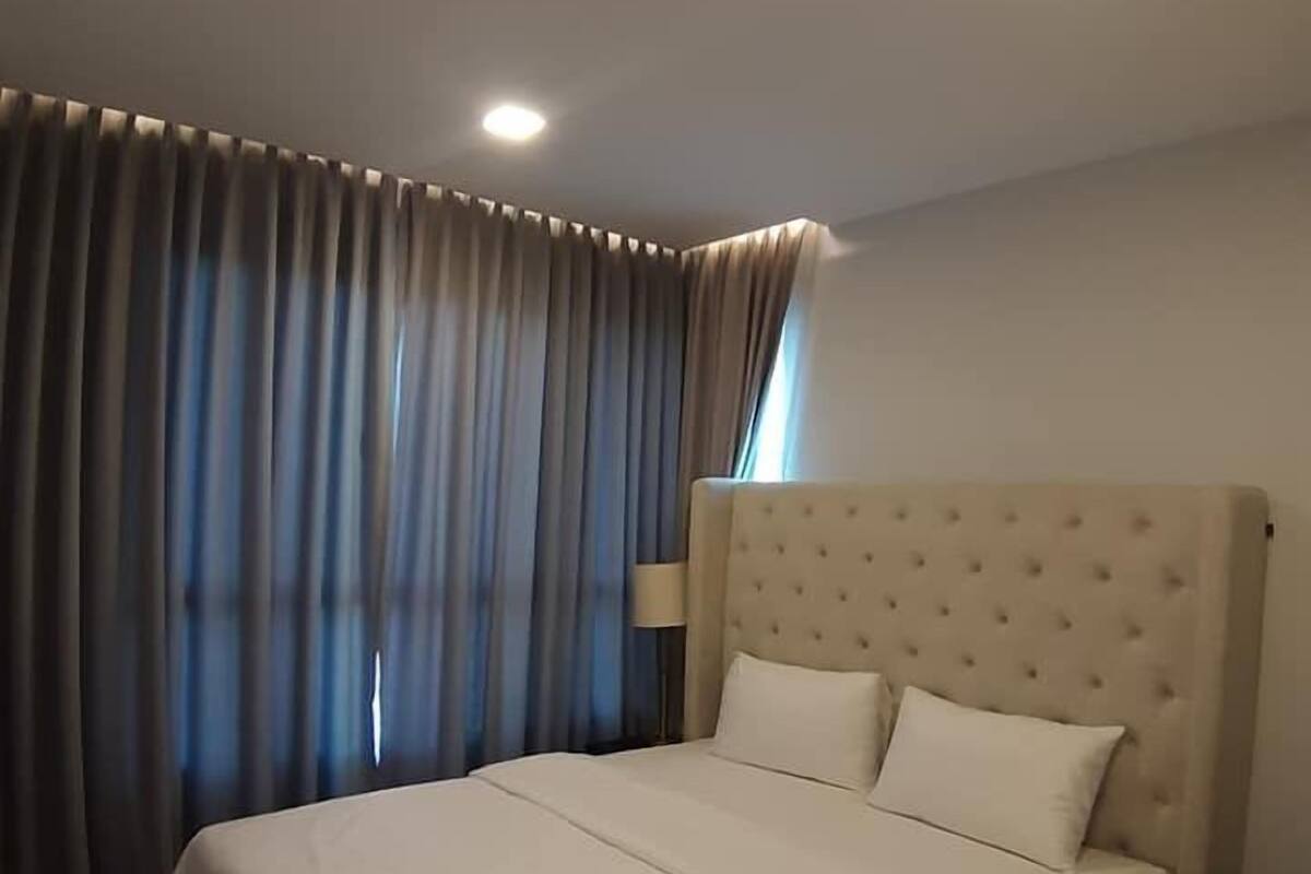 A hotel room with a large bed, curtains, and a ceiling light.