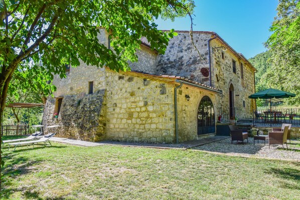 A stone building with a courtyard, outdoor seating, and a pergola.