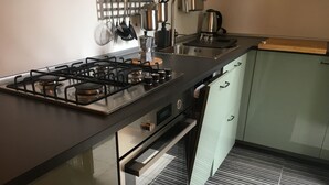 A modern kitchen with a gas stove, oven, and stainless steel appliances. - Family room with 4 beds, private bathroom and study with desk.  (Sarzana)