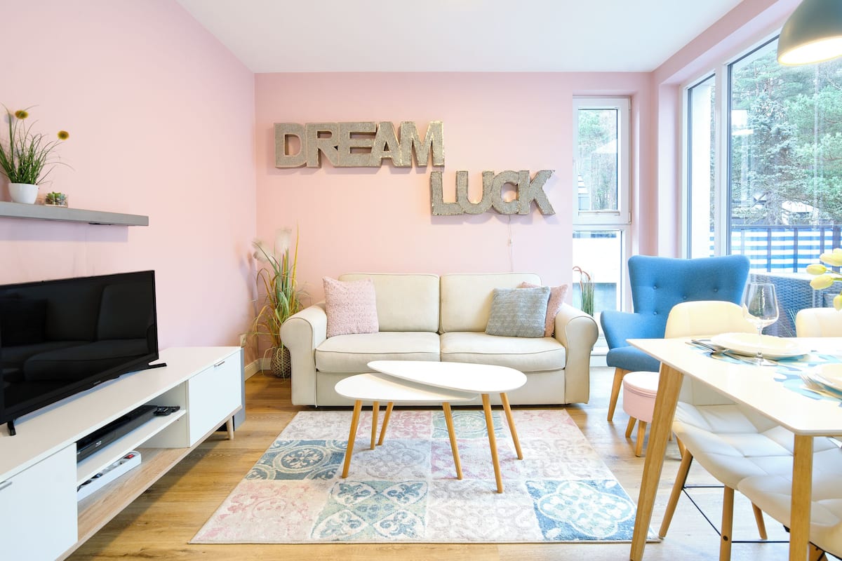 A modern living room with a sofa, coffee table, TV, and a dining area with chairs and a table.