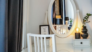 A white vanity with a mirror, a framed picture, and a bedside lamp. - BlueBell Hotel (Bratislava)