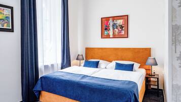 Une chambre d’hôtel avec un grand lit, deux tables de chevet, une commode, une fenêtre avec des rideaux et un tableau encadré au mur.