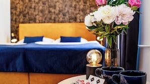 A hotel room with a bed, a vase of flowers, and two mugs on a table. - BlueBell Hotel (Bratislava)