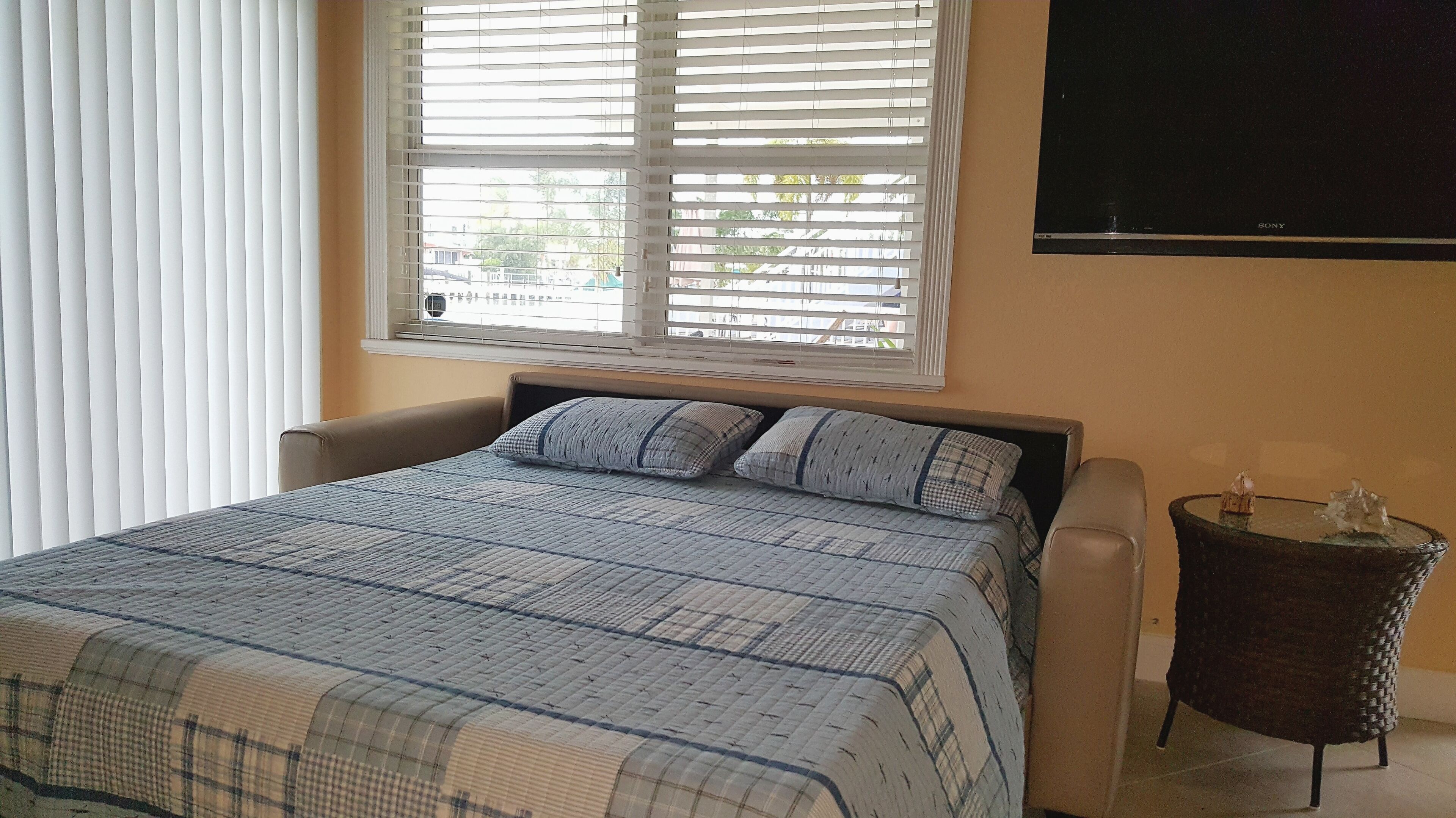 Une chambre à coucher avec un lit, une table de chevet et un téléviseur fixé au mur.