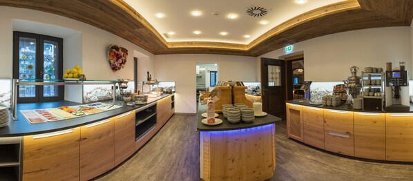 A modern kitchen with wooden cabinets, a central island with a blue light, and various kitchen appliances. - Der Siegeler - this lifestylehotel rocks (Mayrhofen)