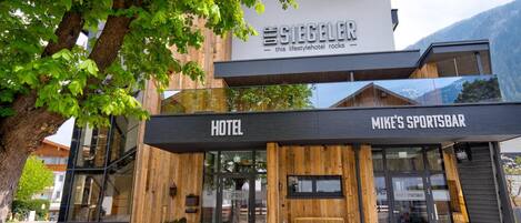 Un hotel de diseño moderno, con un letrero destacado que dice 'The Siegel' y un bar deportivo llamado 'Mike's Sportsbar' debajo.