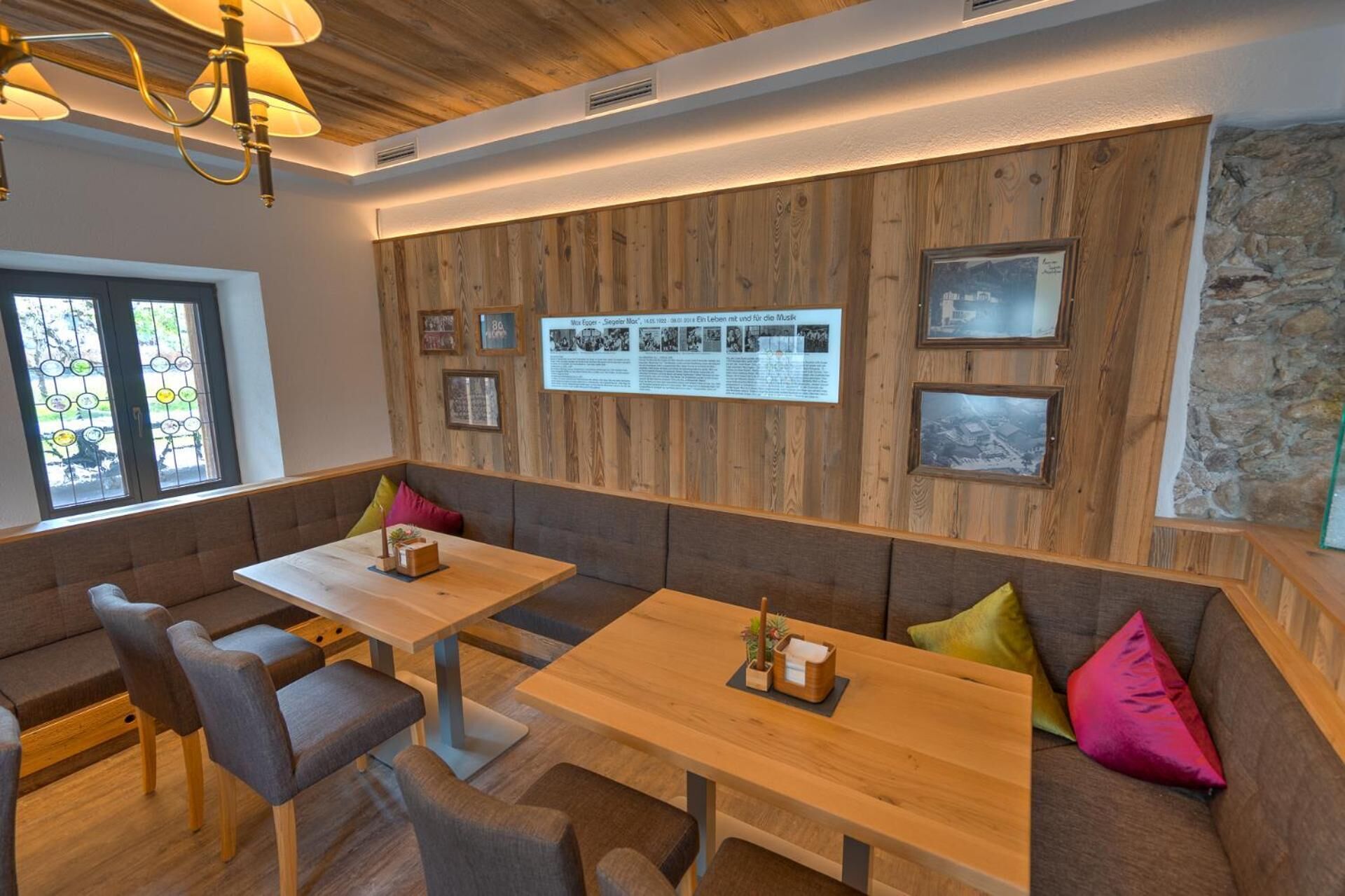 Un restaurante con paredes de paneles de madera, una mesa larga y un banco con cojines de colores.