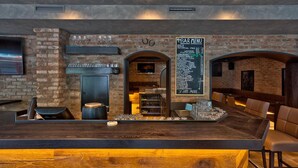 A bar area with a brick wall, a menu board, and seating. - Der Siegeler - this lifestylehotel rocks (Mayrhofen)