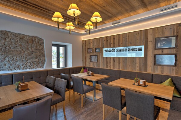 Interior de restaurante con paredes de madera, detalles de piedra y diversas opciones de asientos, incluidas cabinas y mesas.