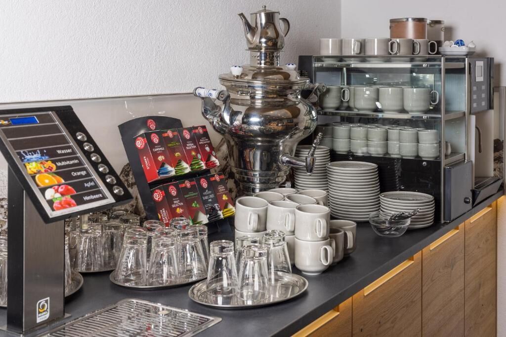 Un aparador tipus bufet amb una màquina de cafè, diversos plats i un dispensador de begudes.