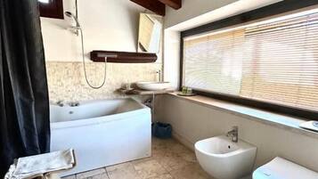 Une salle de bain avec une baignoire, un bidet et un lavabo.