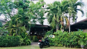 A lush garden with a motorbike parked in front of a building labeled "HOTEL GUEST HOUSE". - Buddy Guesthouse (Chiang Mai)