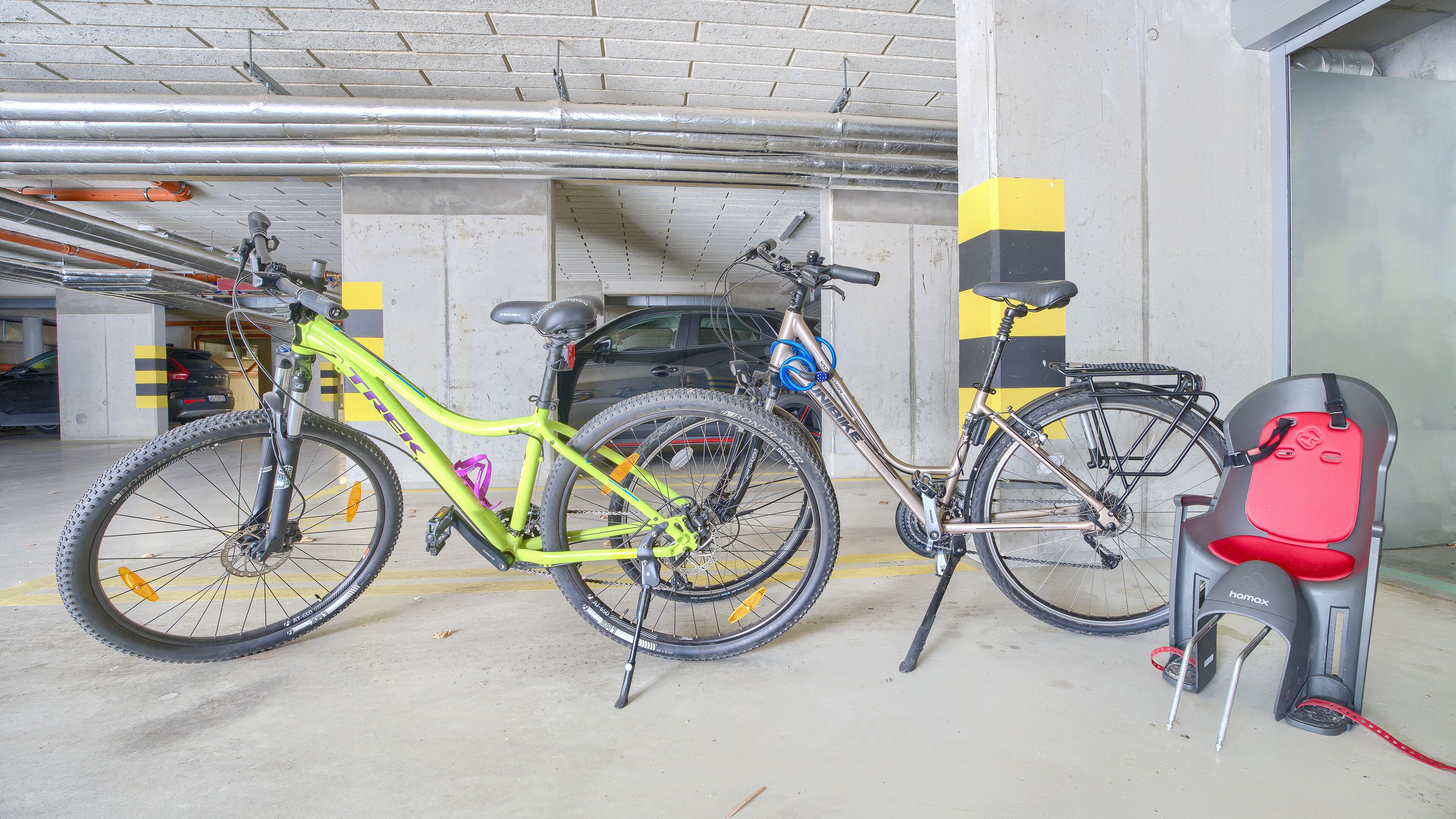 A parking garage with bicycles and a stroller.