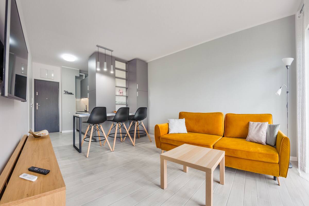 Een moderne woonkamer met een bank, salontafel en een eethoek met stoelen.