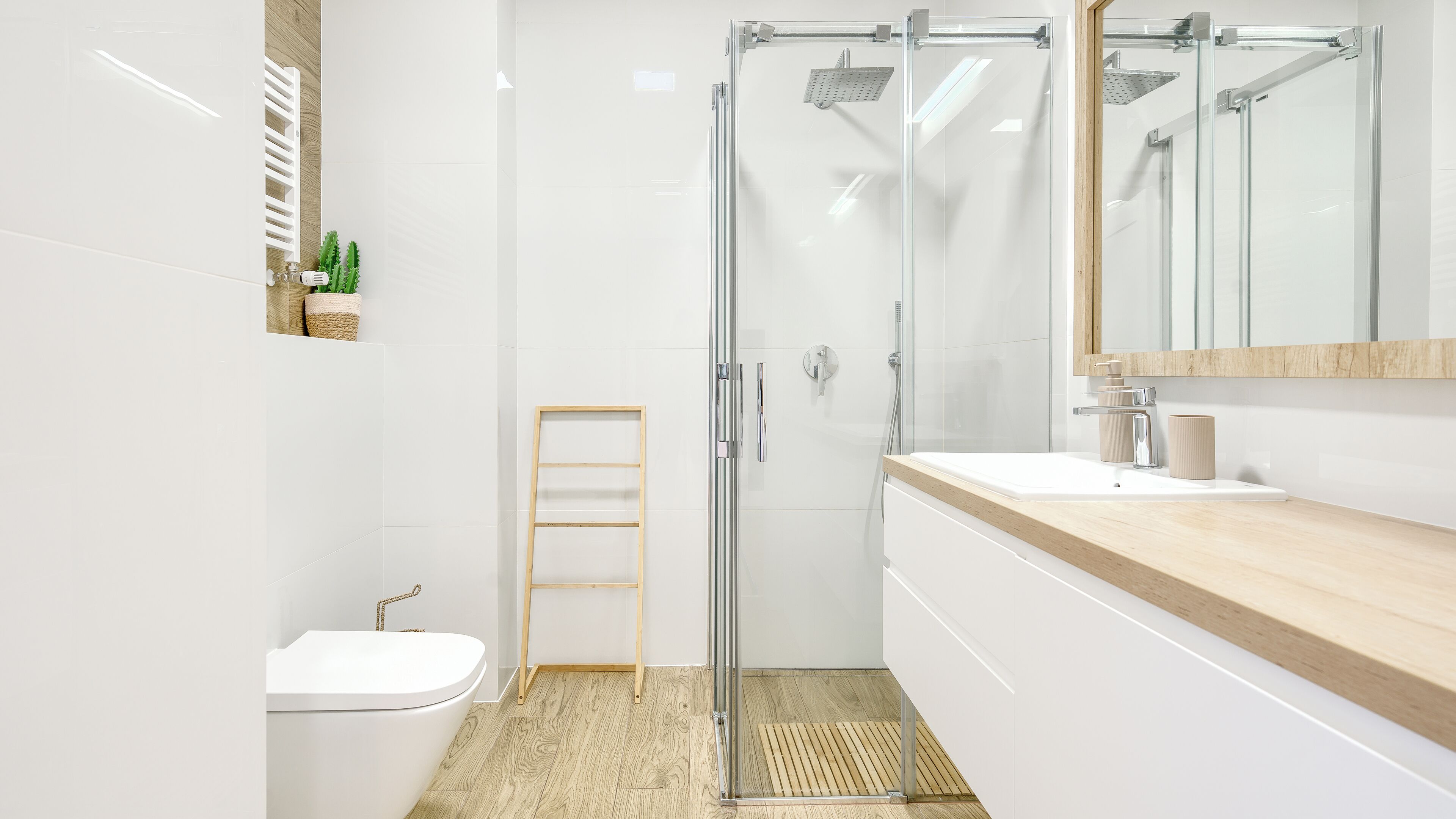 A modern bathroom with a glass shower enclosure, a wooden vanity, and a toilet.