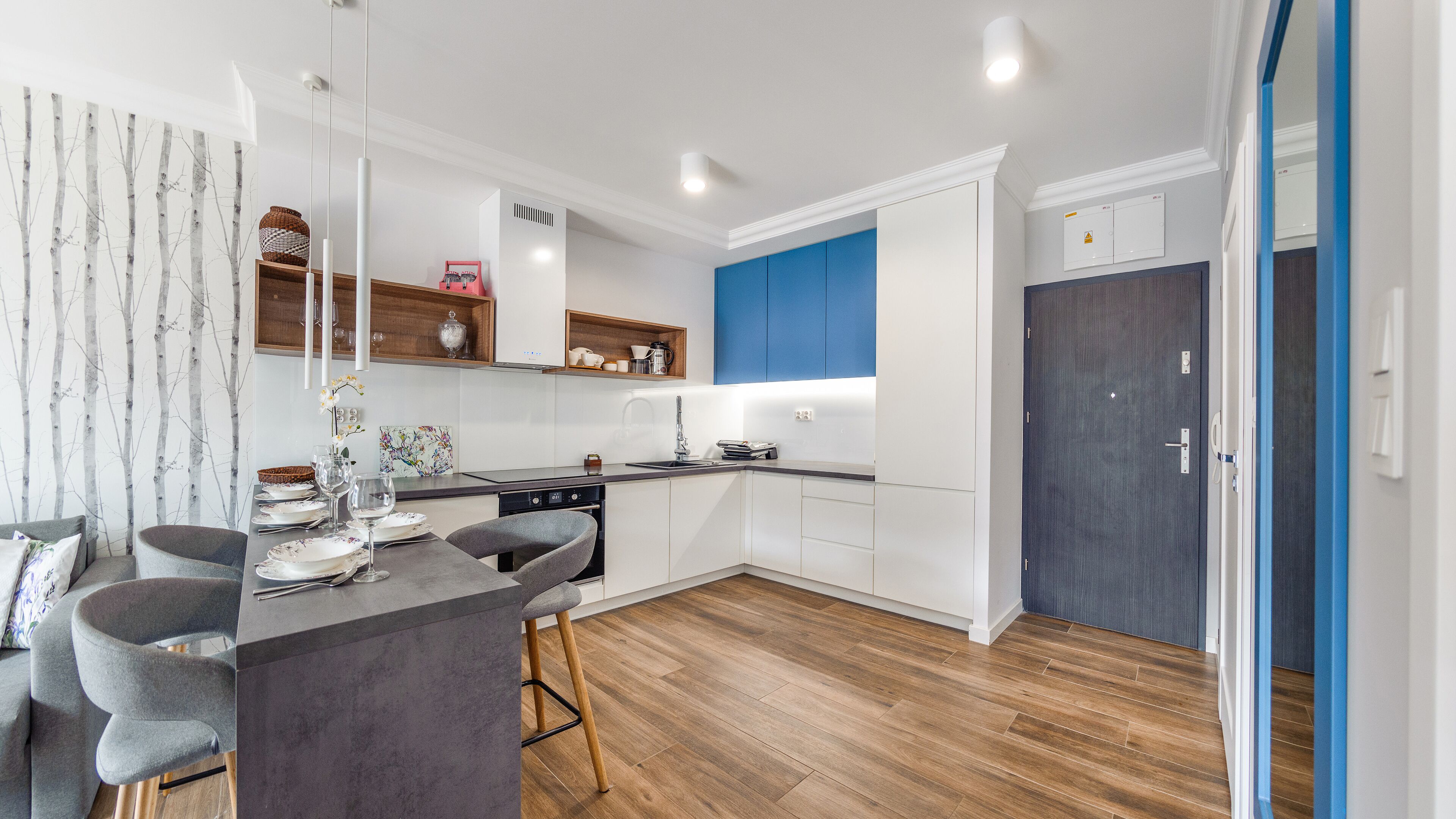A modern kitchen with white cabinetry, a wooden countertop, and a blue accent wall.