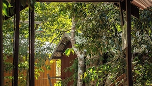 Un pont en bois mène à un chalet appelé « Vista do Lago Jungle Lodge », qui présente une structure en bois rustique et offre une vue sur la forêt environnante.