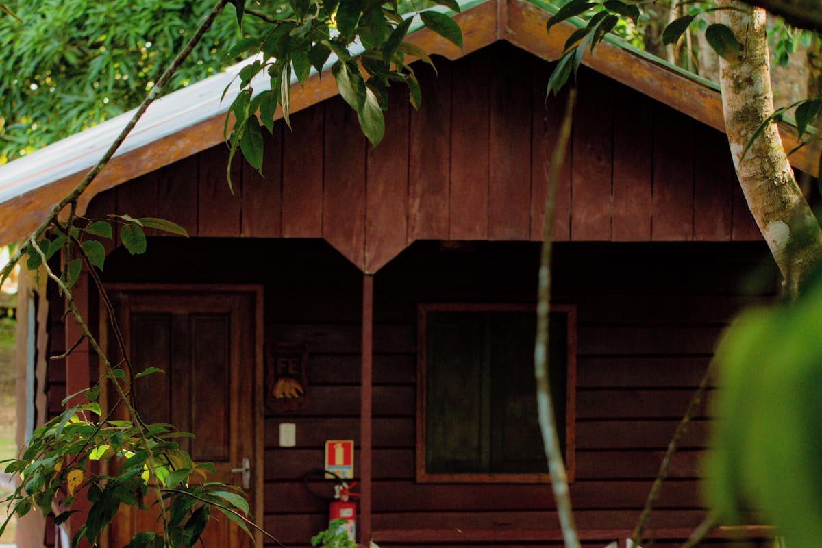 Une cabane en bois avec une véranda, une porte et une fenêtre.