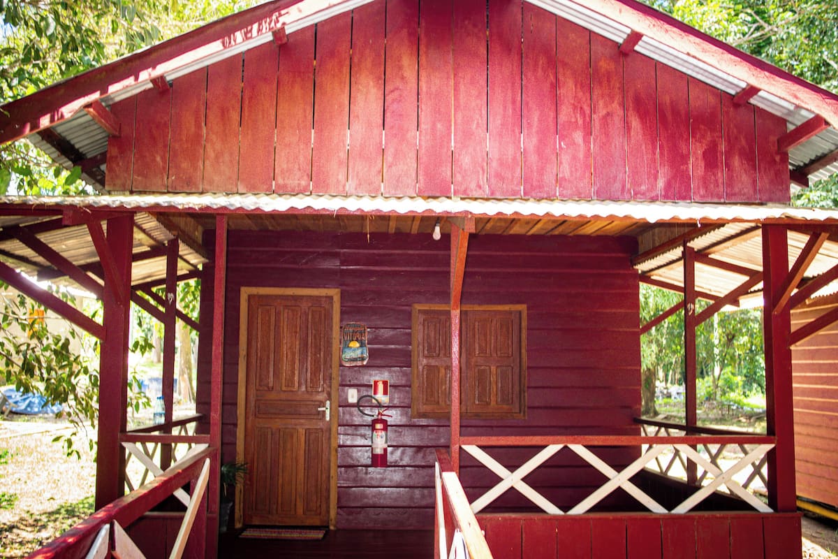 Une cabane en bois avec une véranda, deux portes et une petite fenêtre.