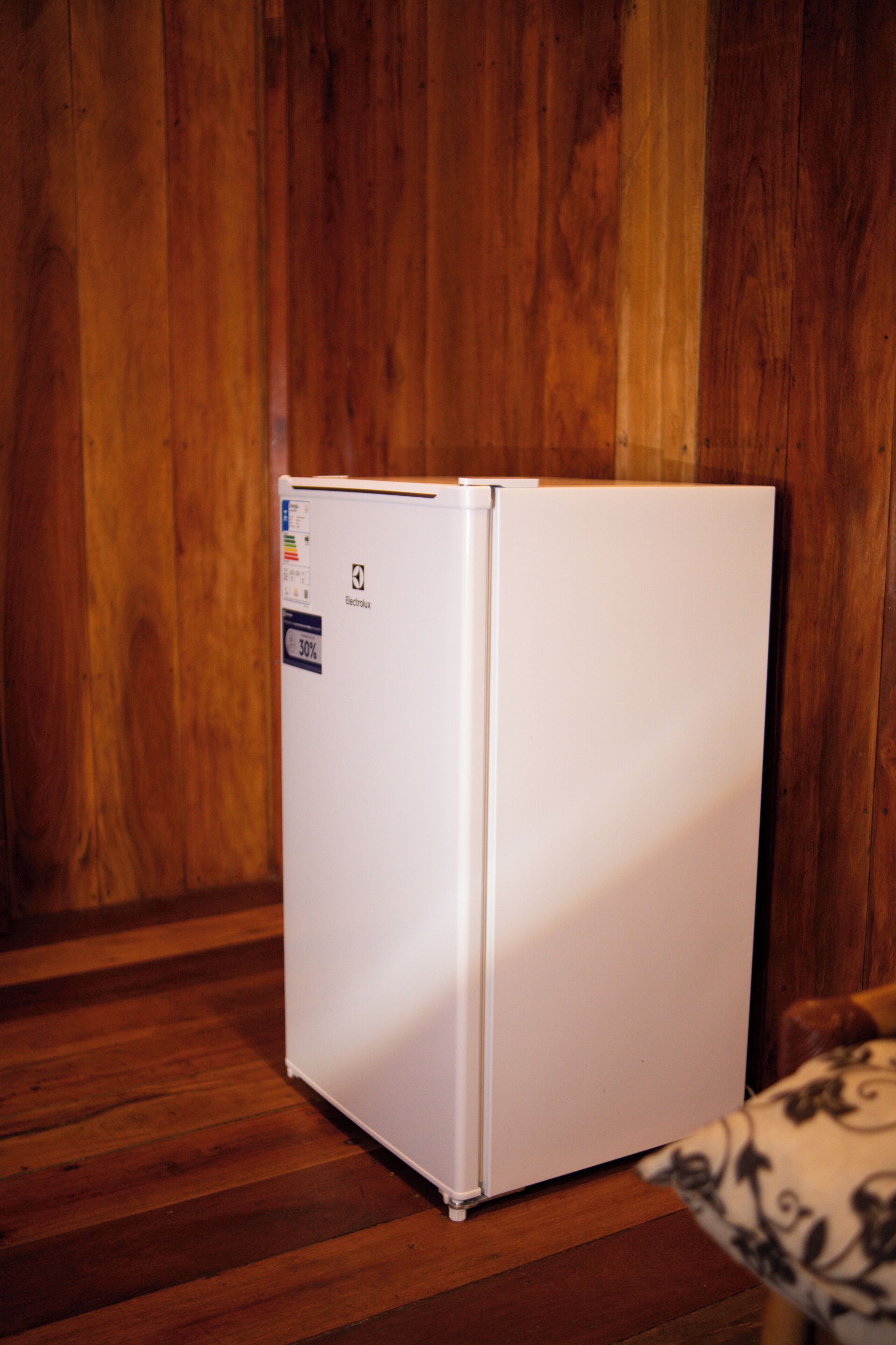 Un refrigerador blanco en una habitación con paredes y suelo de madera.