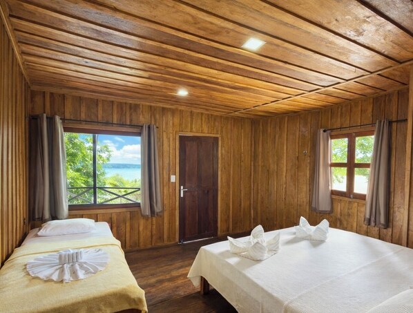 Een houten kamer met twee bedden, een raam met uitzicht en een deur.