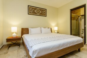 A neatly made bed with a patterned bedspread, two bedside lamps, and a decorative wall piece above the bed.