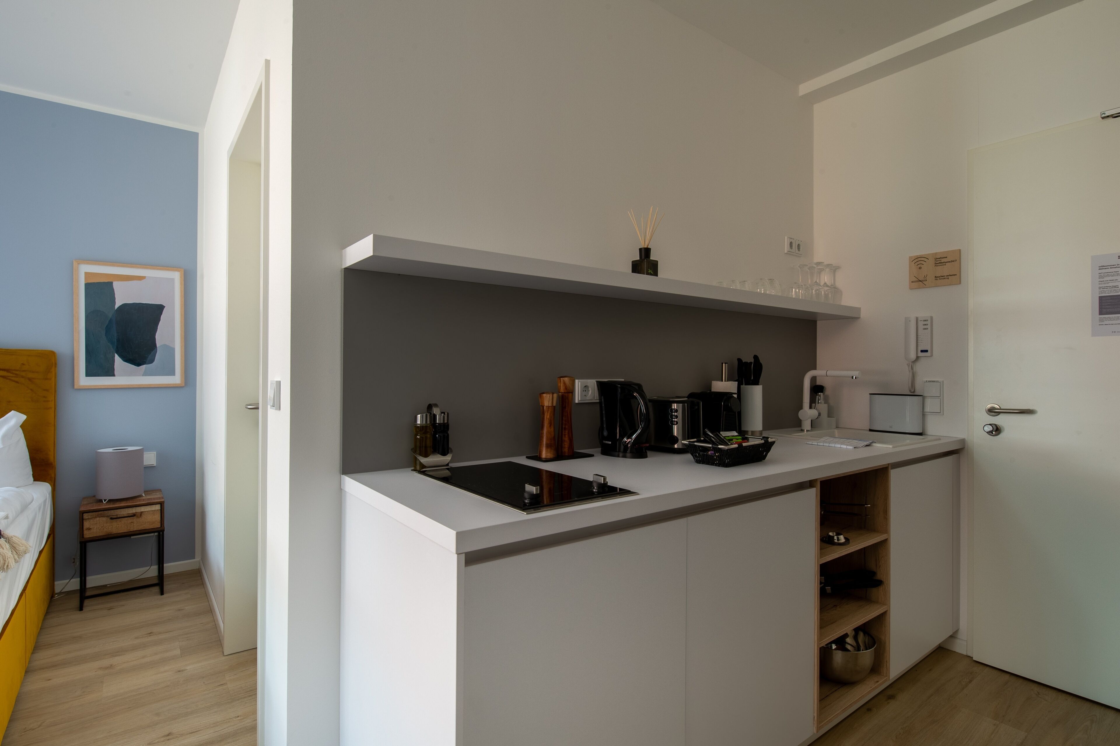 Uma cozinha compacta com bancada branca, cafeteira e pia.