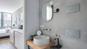 Ein modernes Badezimmer mit einem runden Waschbecken, einem Spiegel und einem Handtuchhalter.