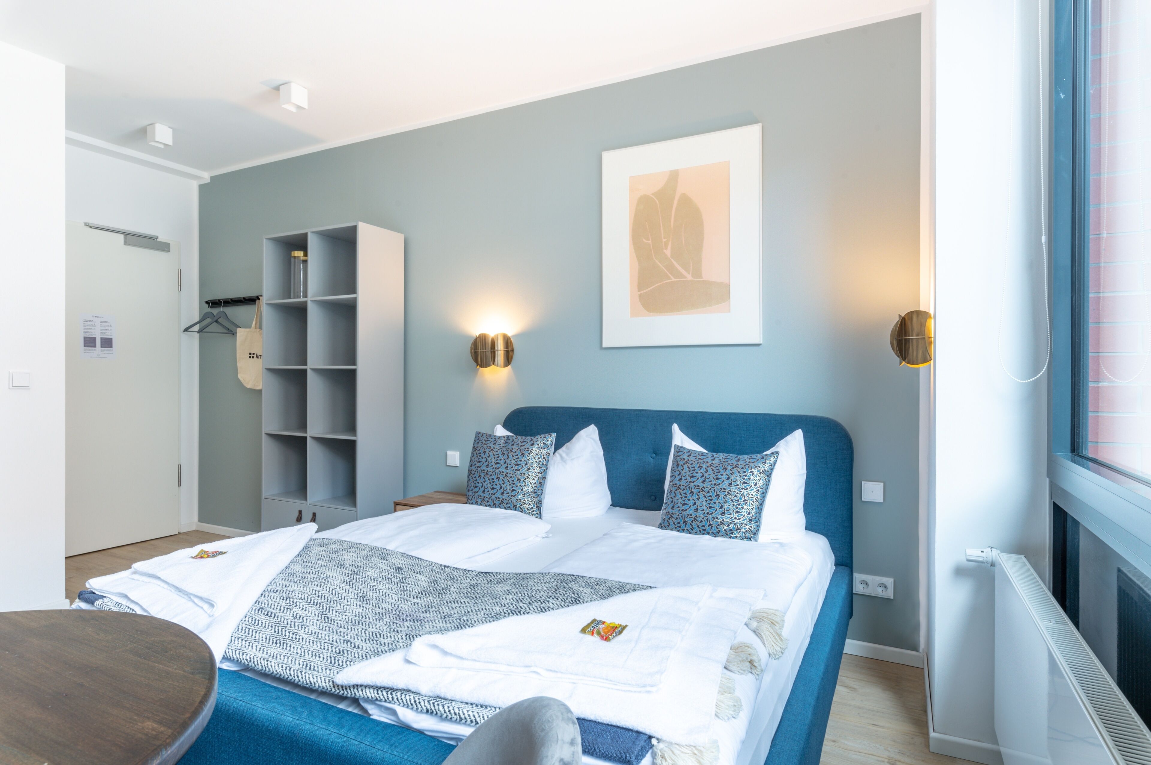 Un dormitorio moderno con cama, mesitas de noche, armario y ventana.