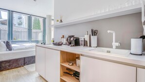 Una cocina moderna con horno integrado, un lavamanos y una ventana con vistas a un balcón.