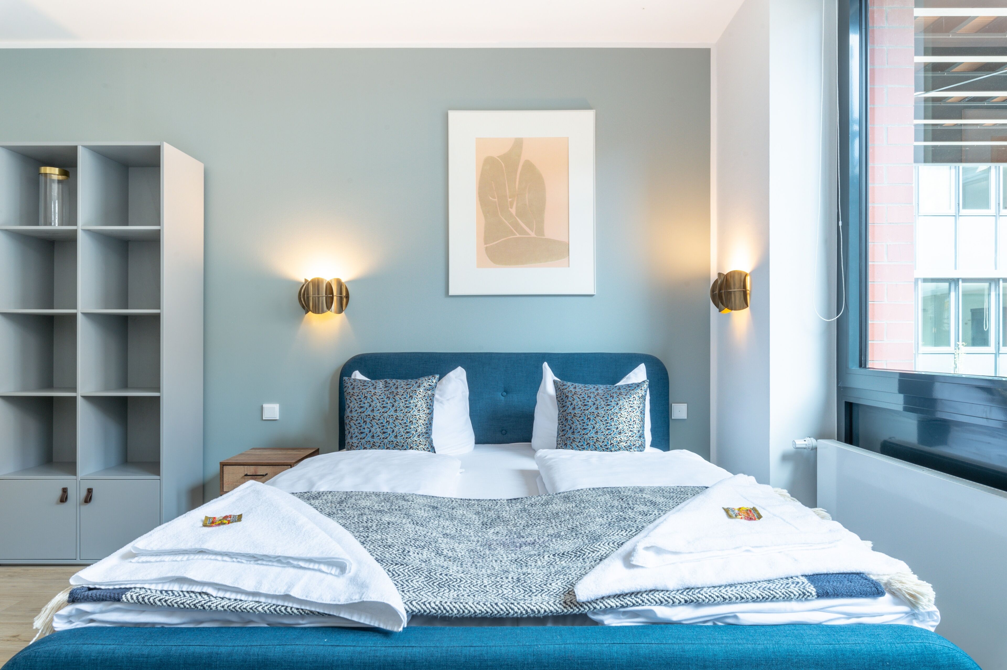 Una camera da letto ordinata con un letto, comodini, un armadio e un'opera d'arte incorniciata al muro.
