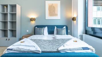 Een keurig opgemaakt slaapkamer met een bed, nachtkastjes, een kledingkast en een lijst met kunstwerk aan de muur.