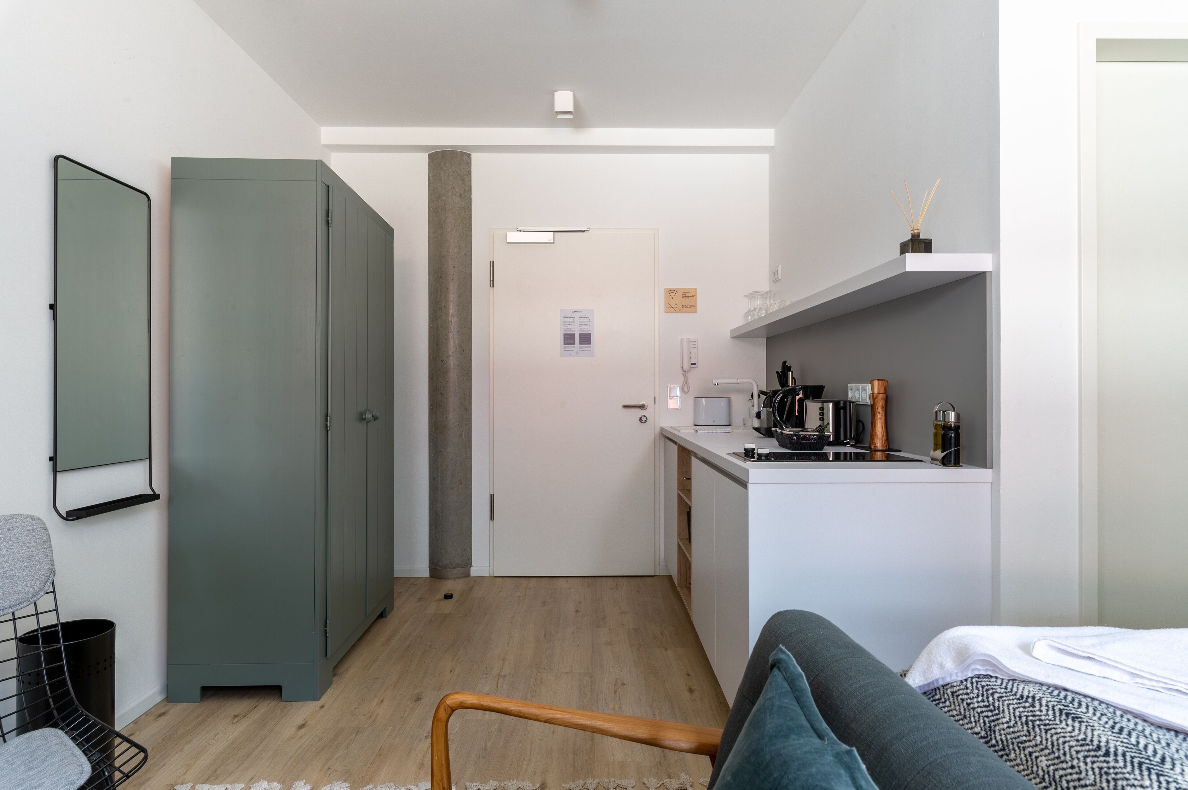 Un espacio habitable pequeño con kitchenette, cama y una zona de estar.