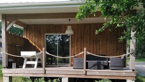 A wooden deck with outdoor seating, a rope barrier, and a hanging light fixture. - Homerez - Charming house Audenge with garden (Audenge)