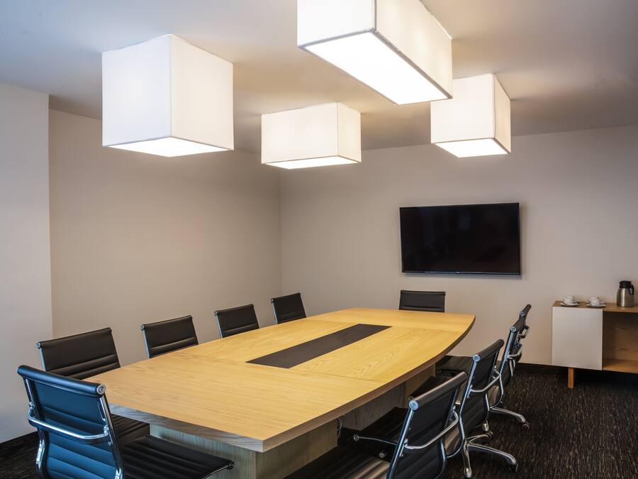 A conference room with a long table, black chairs, and modern pendant lighting.