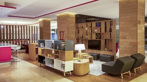 A modern living area with a bar, seating, and a fireplace. - Fiesta Inn Celaya Galerías (Celaya)