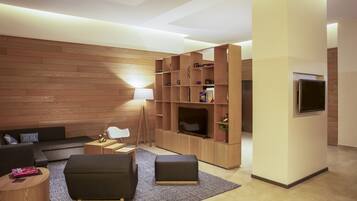 Una sala de estar moderna con pared de madera, un sofá, una mesa de centro, un televisor y una estantería.