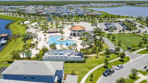 Vista aérea de un complejo turístico con piscina central, varias villas y un lago.