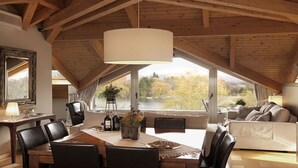 Un comedor con una mesa de madera, sillas y un amplio ventanal con vistas a un paisaje pintoresco.