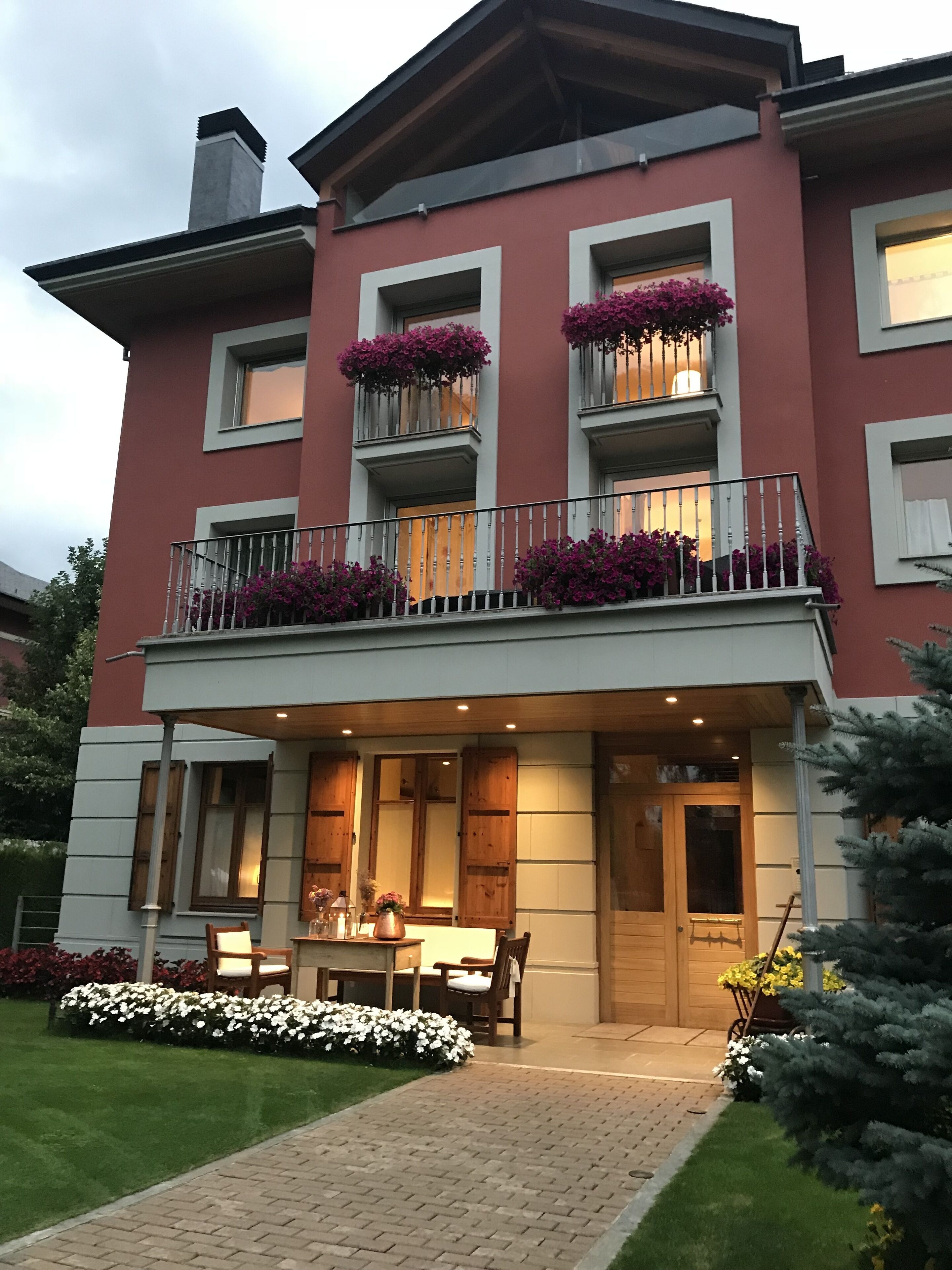 A two-story building with a balcony, a wooden door, and a small outdoor seating area with a table and chairs.