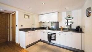 A modern kitchen with white cabinets, a black countertop, and built-in appliances.