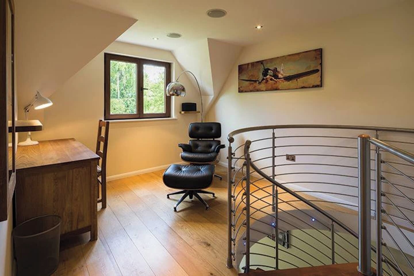 A room with a desk, chair, and a spiral staircase.