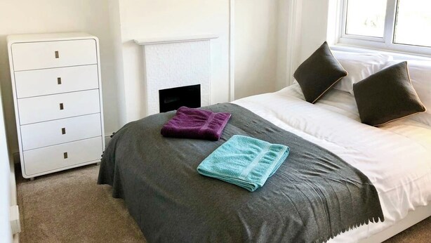 A bedroom with a bed, a wardrobe, a window, and a door.